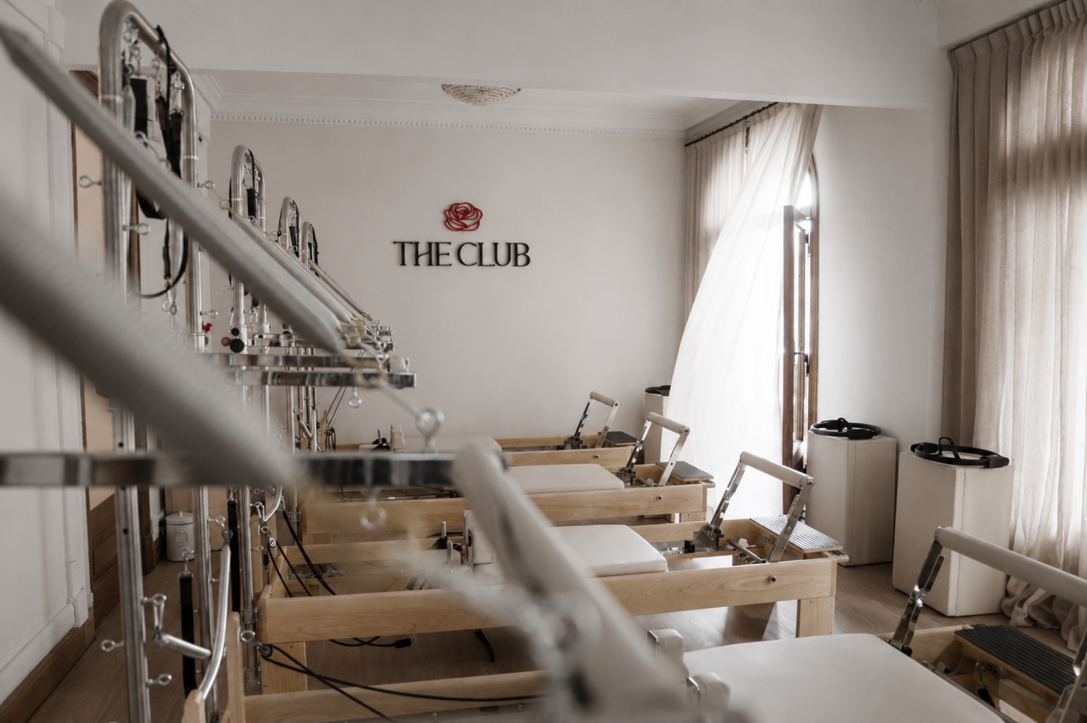 Sala de pilates reformer de The Club, luz natural y logo de la marca en la pared